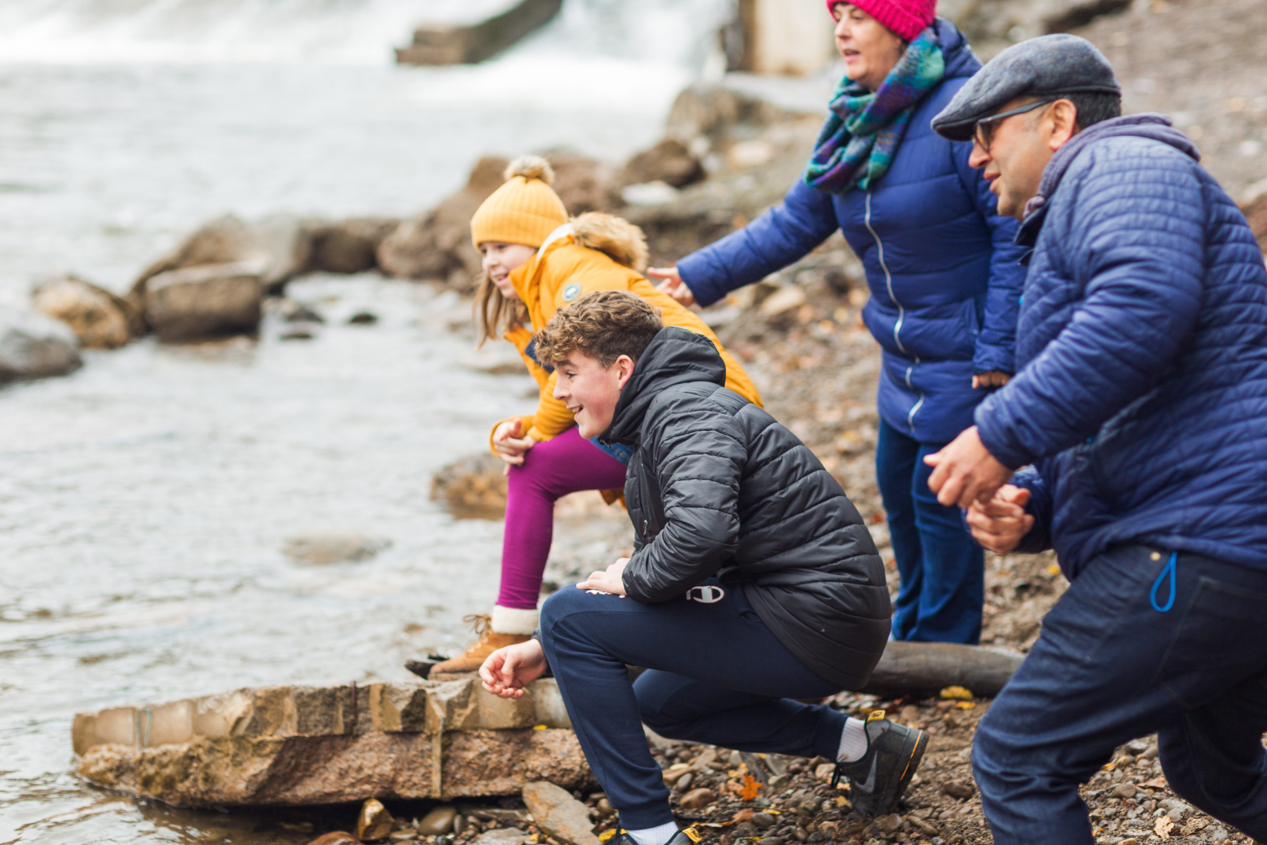Family of 2 adults and 2 children together on coastline