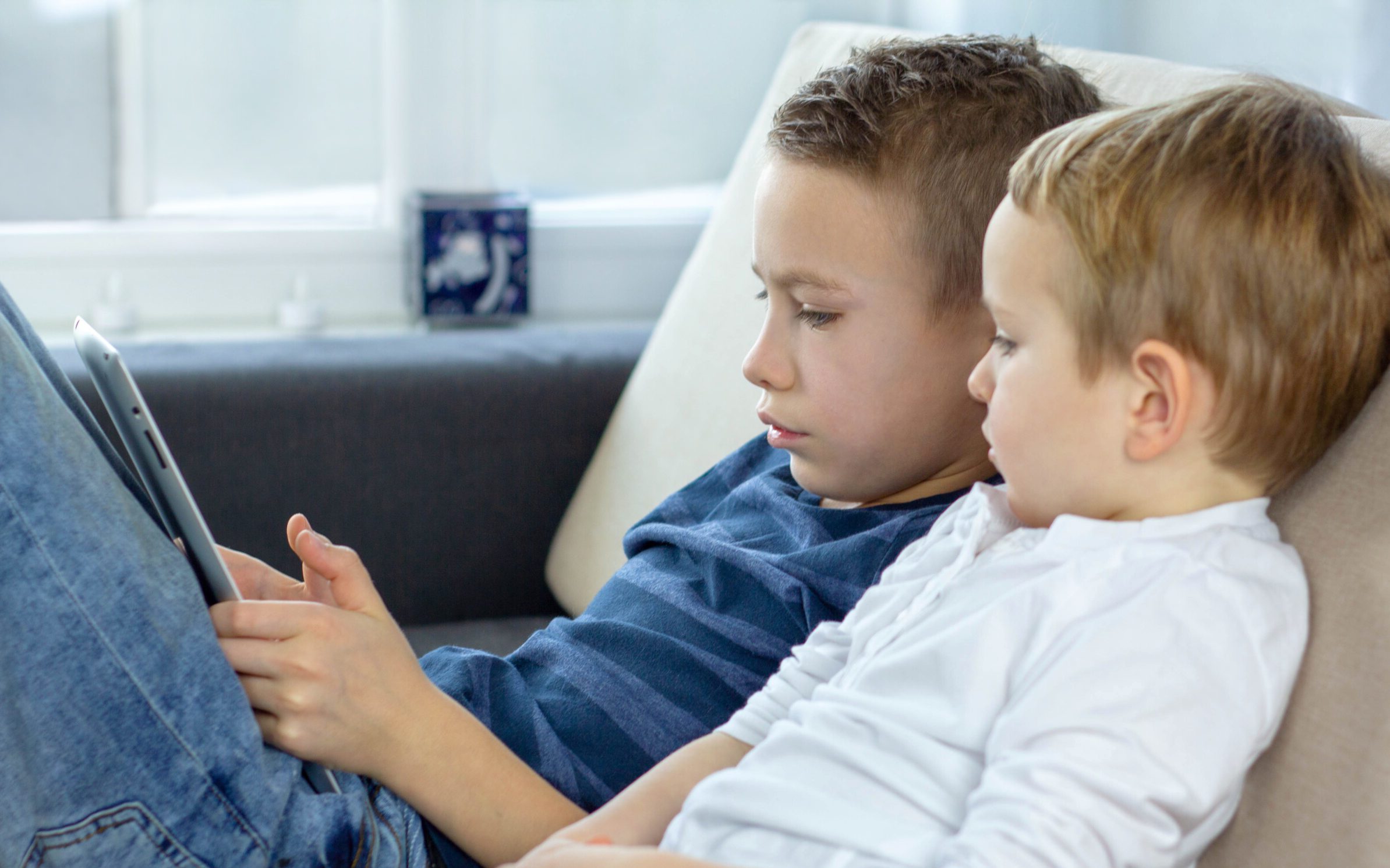 Two boys sitting together using touchscreen device