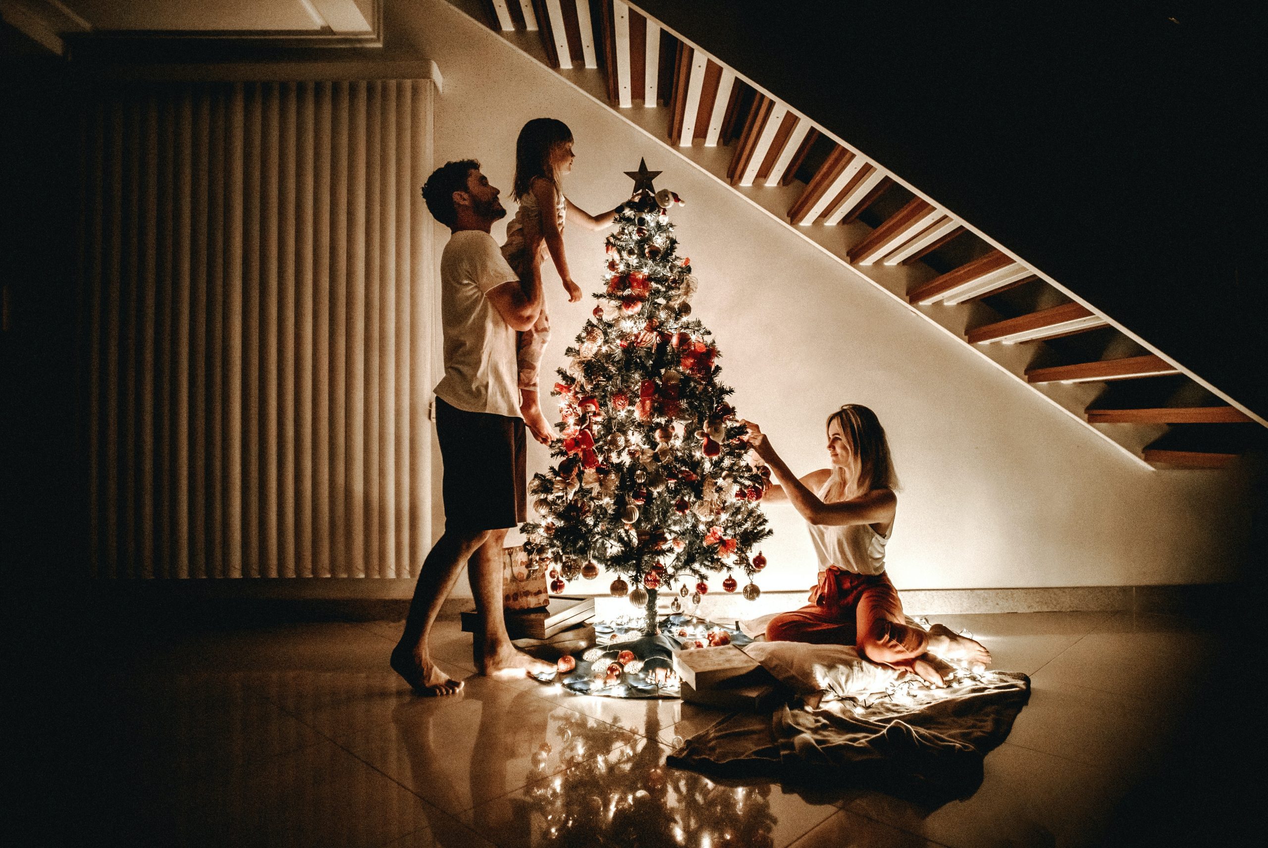 mother and father helping daughter decorate the christmas tree